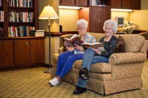 2 Woman Reading Sitting on Couch Together