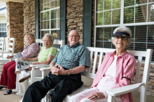 Group of People Sitting Outside and Smiling on White Benches