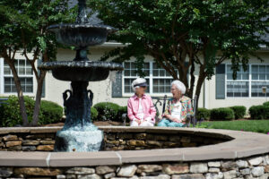 2 Woman Sitting Outside in Front of Water Fountain