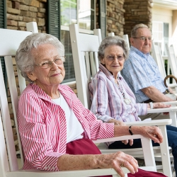 Group of People Smiling Outside on Rocking Chairs